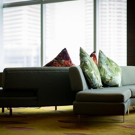 Traders Hotel, Κουάλα Λουμπούρ Εξωτερικό φωτογραφία The photo shows a contemporary lounge area featuring a modern sofa with a unique design. The sofa is upholstered in a muted color and is adorned with vibrant decorative pillows featuring floral patterns. It is positioned in front of large windows tha