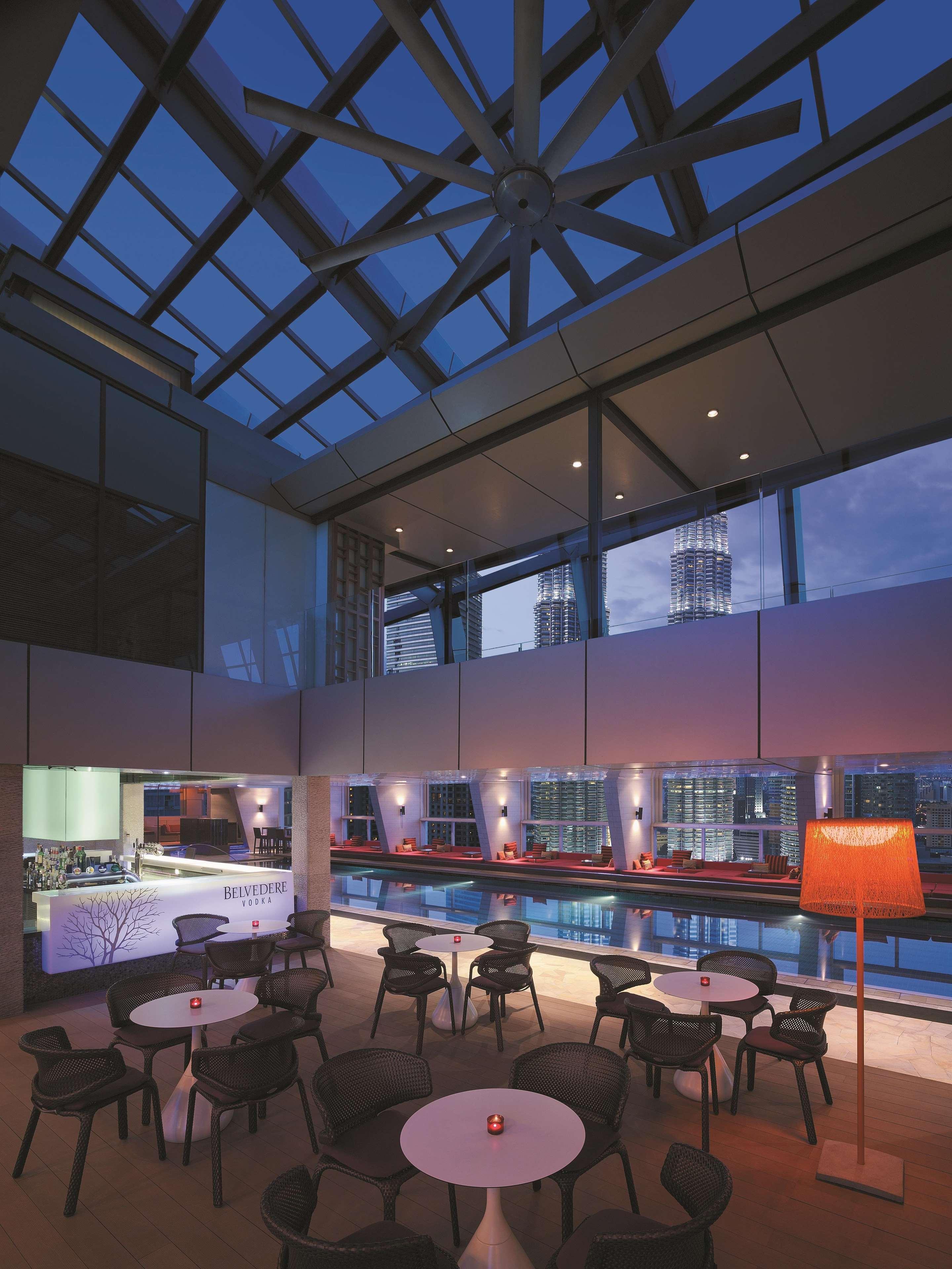 Traders Hotel, Κουάλα Λουμπούρ Εξωτερικό φωτογραφία The photo showcases a stylish modern interior, featuring a spacious room with large glass windows that provide a stunning view of the skyline. The lighting is soft and ambient, creating a warm atmosphere as evening approaches. There are sleek furnitu