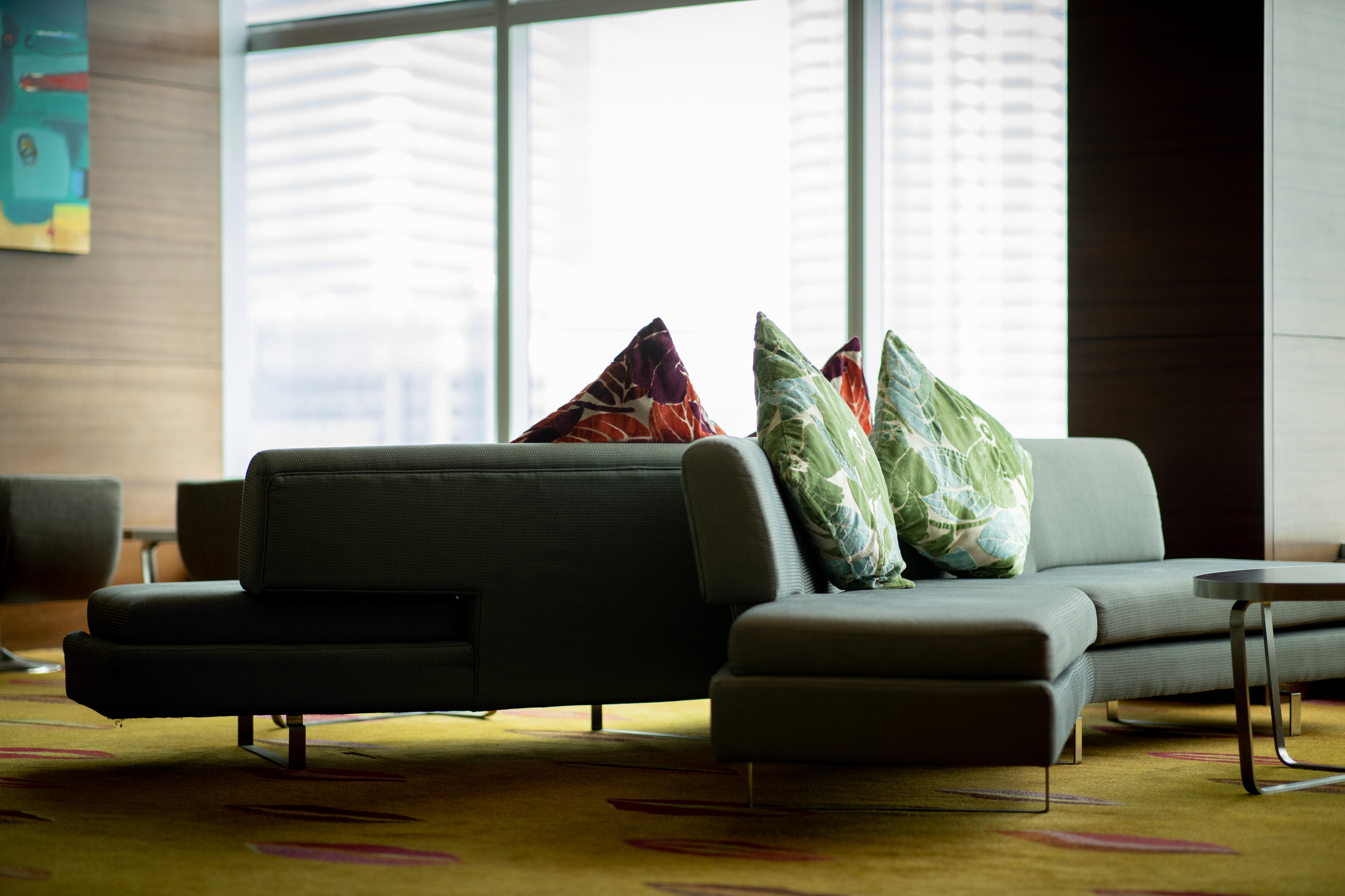 Traders Hotel, Κουάλα Λουμπούρ Εξωτερικό φωτογραφία The photo shows a contemporary lounge area featuring a modern sofa with a unique design. The sofa is upholstered in a muted color and is adorned with vibrant decorative pillows featuring floral patterns. It is positioned in front of large windows tha