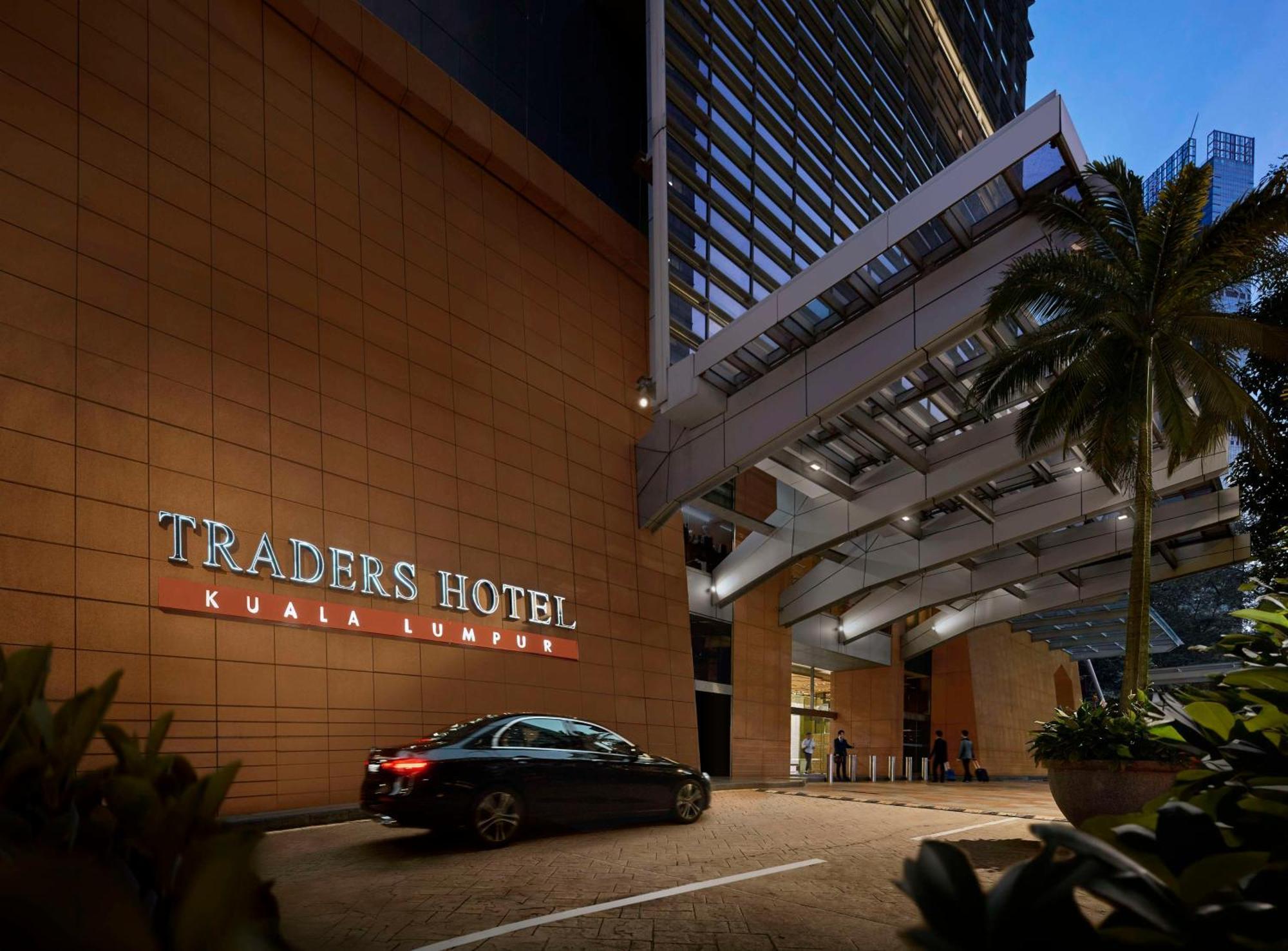 Traders Hotel, Κουάλα Λουμπούρ Εξωτερικό φωτογραφία The photo shows the entrance of Traders Hotel in Kuala Lumpur. It features a modern architectural design with a prominent sign displaying the hotel name. There is a driveway leading up to the entrance, and a car is parked nearby. The surrounding area