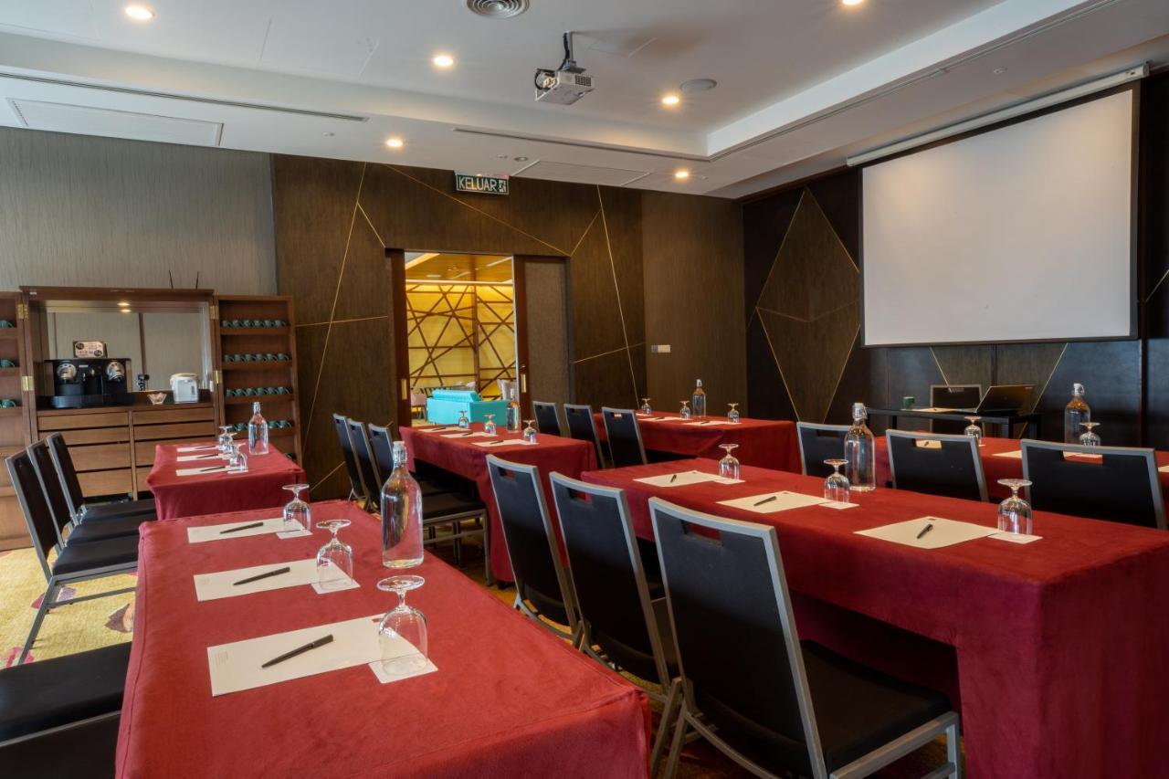 Traders Hotel, Κουάλα Λουμπούρ Εξωτερικό φωτογραφία The photo shows a conference room set up for a meeting or seminar. There are several tables covered with red tablecloths, and each table is equipped with a notepad and pen. Transparent water glasses are placed on each table. The room has a modern des